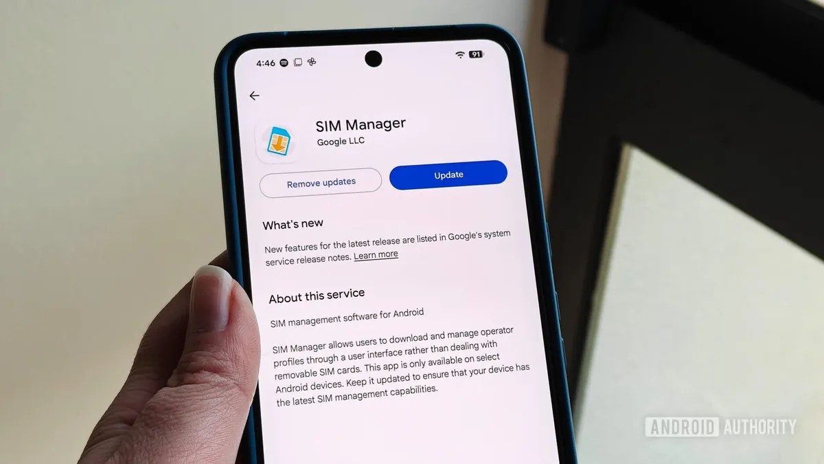 Close-up of a hand holding a smartphone displaying the SIM Manager app update screen with 'Remove updates' and 'Update' buttons