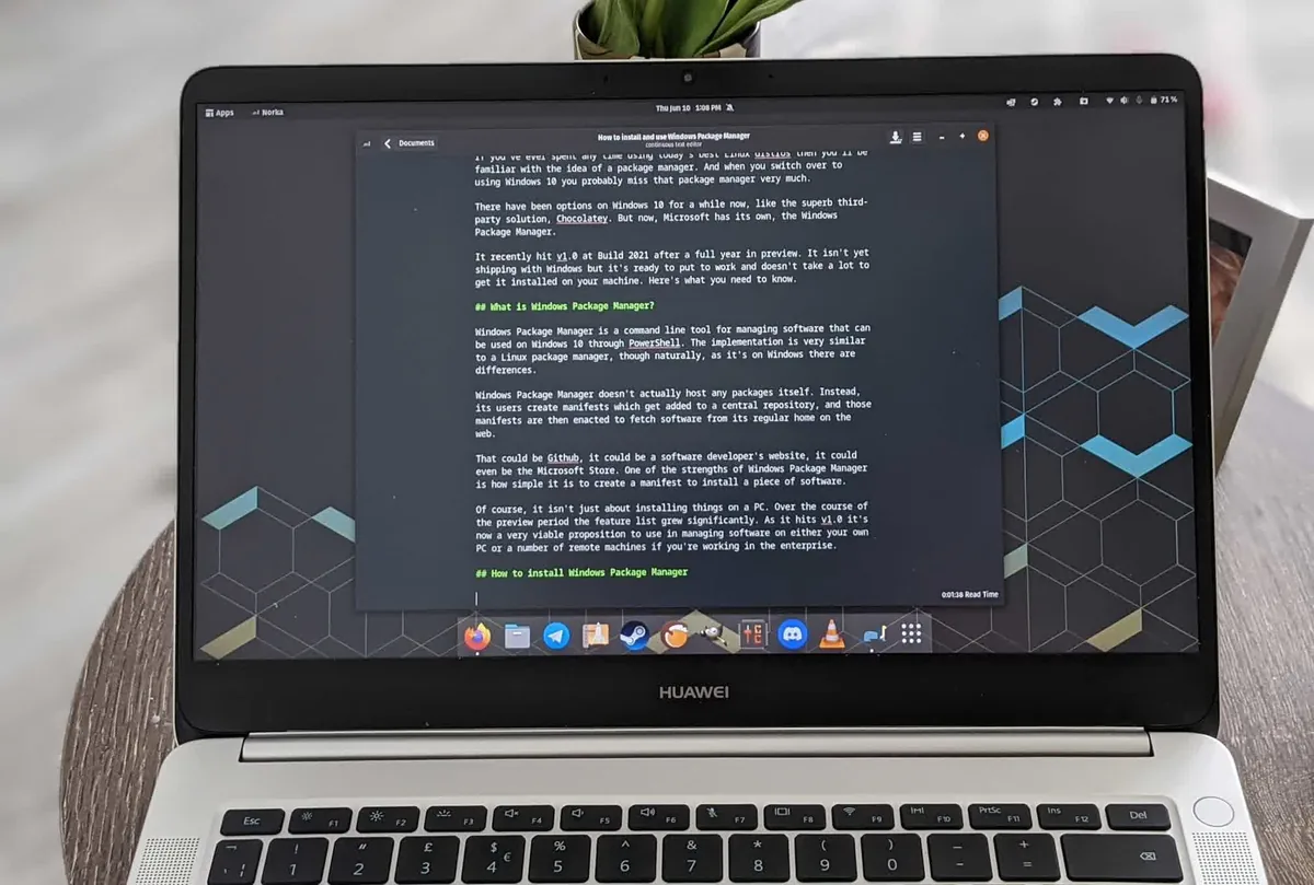 Huawei laptop on a wooden desk shows a dark-mode document about Windows Package Manager, with a small plant resting on the lid above the screen.