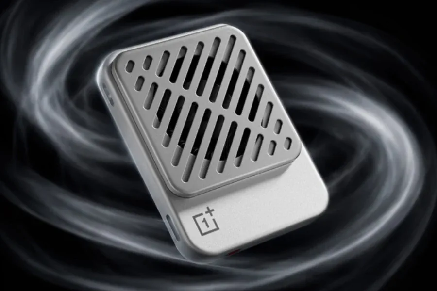 تصویر تبلیغاتی خنک‌کننده مغناطیسی OnePlus Ice Card: رندر محصولی از یک خنک‌کننده کوچک و باریک به رنگ نقره‌ای و سفید با فن داخلی و شبکه‌ای از شیارهای مورب روی بدنه و لوگوی OnePlus در پایین آن که در میان موج‌های دود مانند سیاه و سفید و روی پس‌زمینه تیره شناور است.