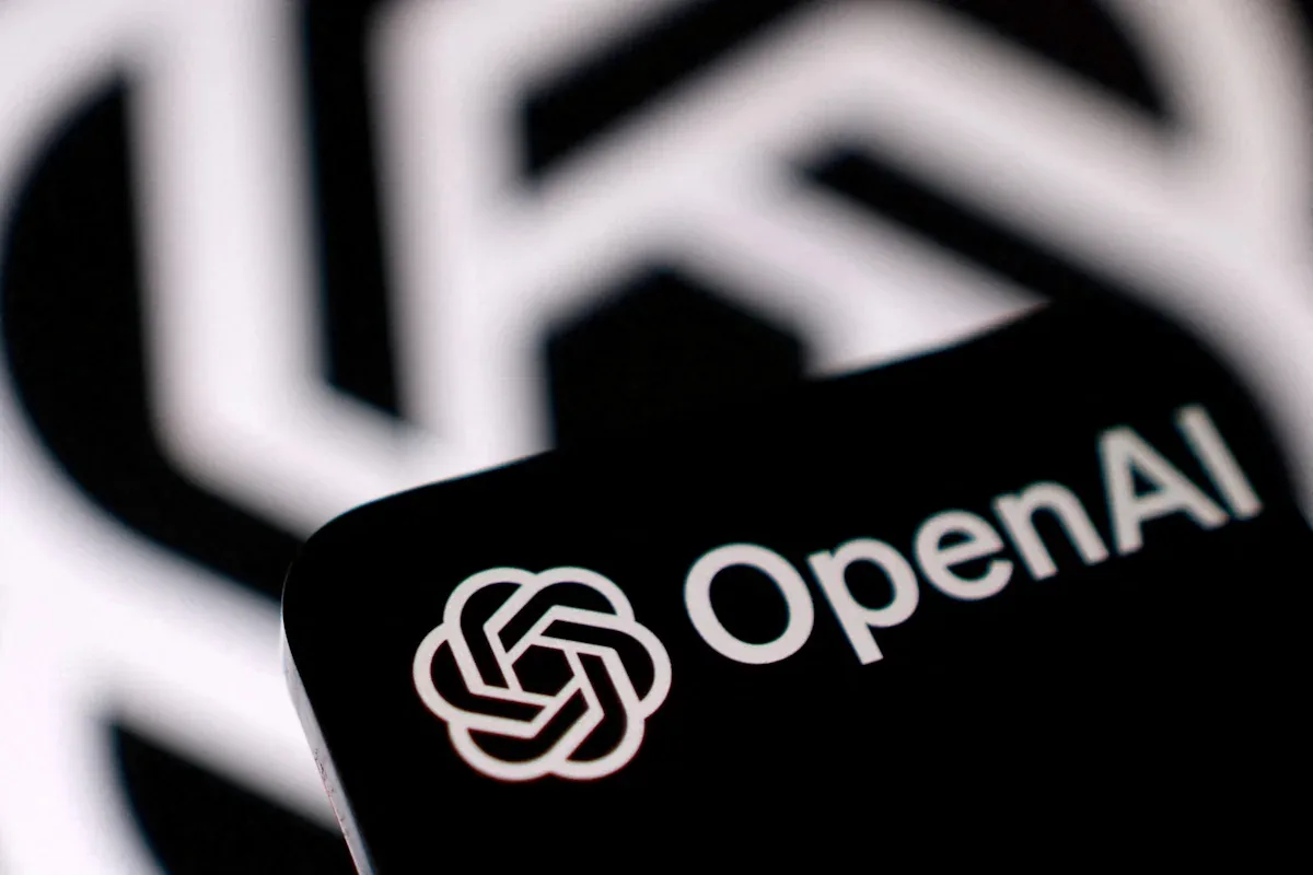 عکس نزدیک از یک کارت با پس‌زمینه مشکی که لوگو و نام OpenAI با رنگ سفید روی آن چاپ شده و در گوشه پایین آن نشان گل‌گشتی شش‌پره این شرکت قرار دارد. در پس‌زمینه، همان لوگوی بزرگ و تارشده با نور سفید روی پس‌زمینه مشکی دیده می‌شود