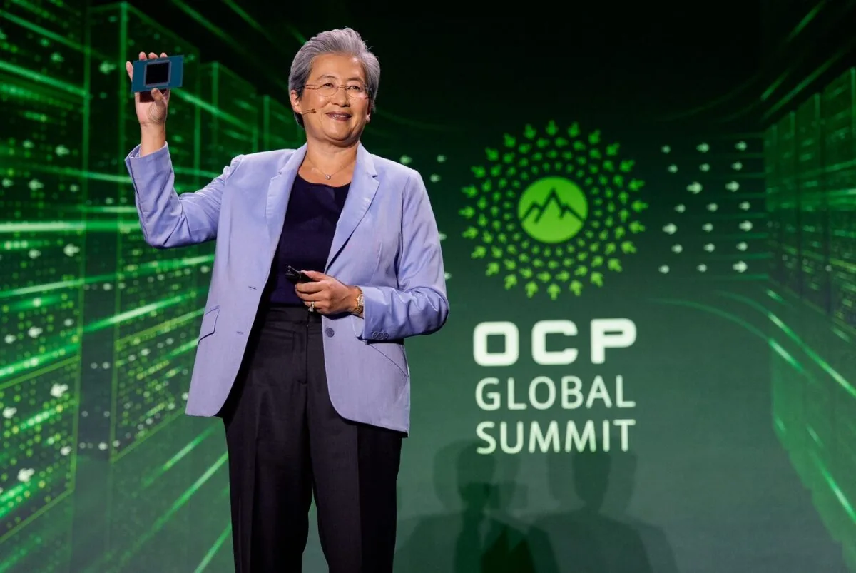 لیزا سو، مدیرعامل AMD، روی صحنه همایش OCP Global Summit در حالی که کت بنفش به تن دارد و تراشه پردازنده سرور را با دست بالا گرفته است.