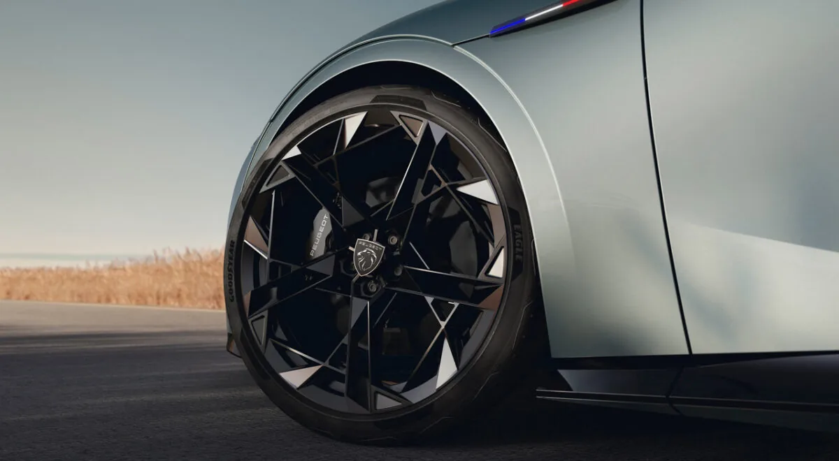 نمای نزدیک رینگ آلومینیومی مشکی پژو RCZ Vision با طراحی هندسی، نشان شیر پژو، کالیپر ترمز اسپرت و بدنه نقره‌ای خودرو
